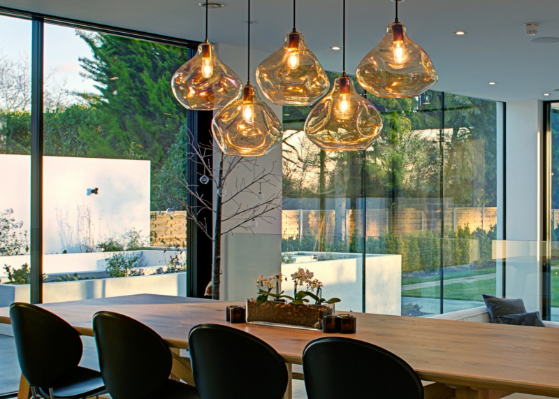 Dining table with bespoke lighting and great views out of large windows into the rear garden area