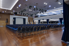 Large Hall, with a stage and many rows of chairs, all setup for a presentation event