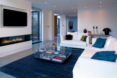 Large fireplace, with large TV over in a recess, with two and three piece white leather seating along with a large glass coffee table