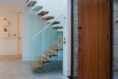 Feature entrance door, showing wood stairs with full glass balustrading to the first floor area