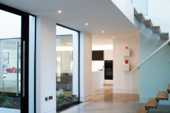 Bespoke hallway showing entrance to kitchen and wood/glass stairs to upper floor